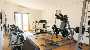 Une salle de sport équipée de divers appareils d’exercice, notamment un banc de développé couché, un tapis de course et un vélo d’appartement.