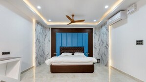 Een slaapkamer met een bed, plafondventilator, inbouwverlichting en marmeren vloer.