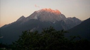 A mountain with a peak, surrounded by trees.