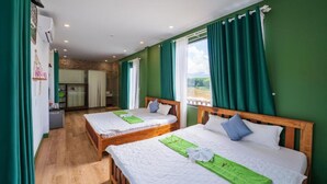 Une chambre d’hôtel avec deux lits, des rideaux verts et une vue sur l’extérieur.