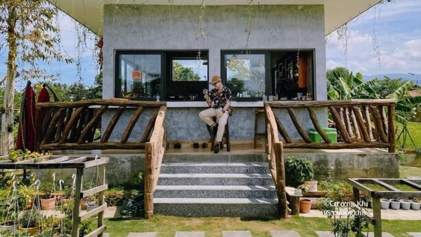 Une maison moderne avec un escalier en bois menant à une porte en verre, entourée de plantes en pot et d’un jardin.