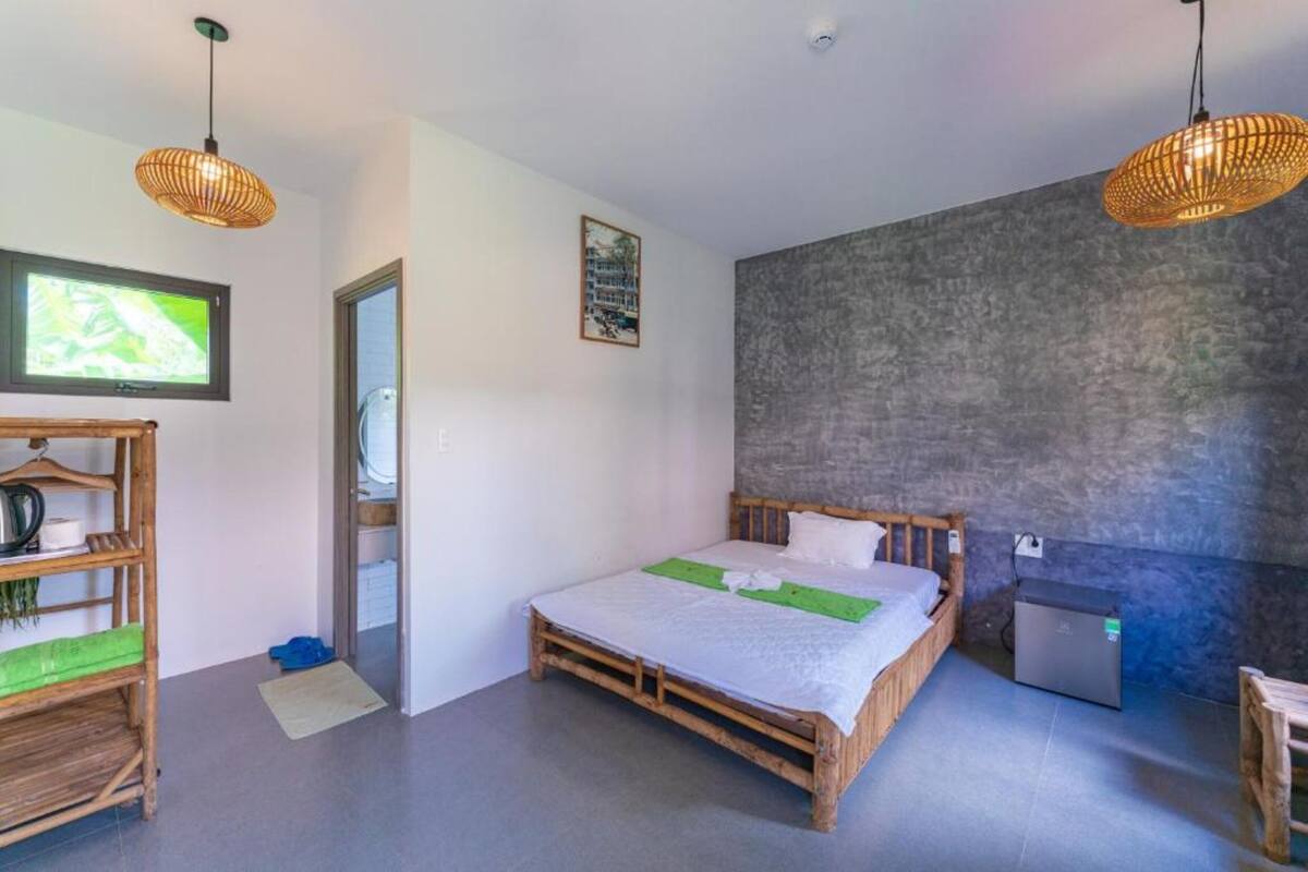 Ein Zimmer mit einem Bett, einem kleinen Tisch, einem Regal, einem Fernseher und einem Kühlschrank.