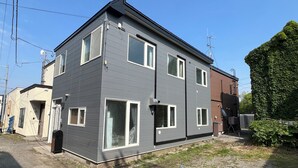 Un immeuble résidentiel moderne à deux étages, avec une façade grise, de nombreuses fenêtres et une antenne parabolique bien visible.