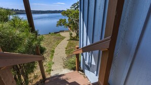 A wooden staircase leading to a deck overlooking a lake, with a clear sky and greenery. - Captain s Retreat in Shelton (Shelton)
