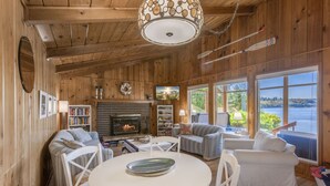 A cozy cabin interior with a fireplace, wooden walls, and large windows overlooking a lake. - Captain s Retreat in Shelton (Shelton)
