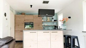 A modern kitchen with wooden cabinets, a built-in oven, and a black range hood. - Spacious Bungalow near Water (Breskens)