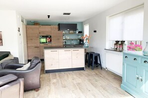 A modern kitchen with a central island, wooden cabinets, and a blue cabinet to the right. - Spacious Bungalow near Water (Breskens)