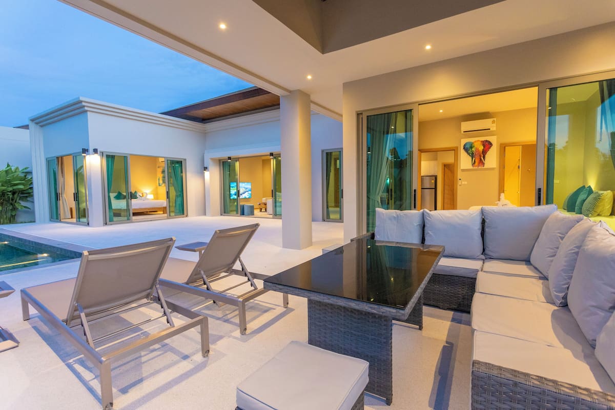 A modern outdoor living area with a pool, lounge chairs, and a sofa.