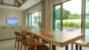 A modern living room with a wooden dining table, chairs, a sofa, and a TV. - Brand New Completed Chalong A  v124 (Chalong)