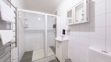 A modern bathroom with a glass-enclosed shower, a white sink, and a mirror above it.