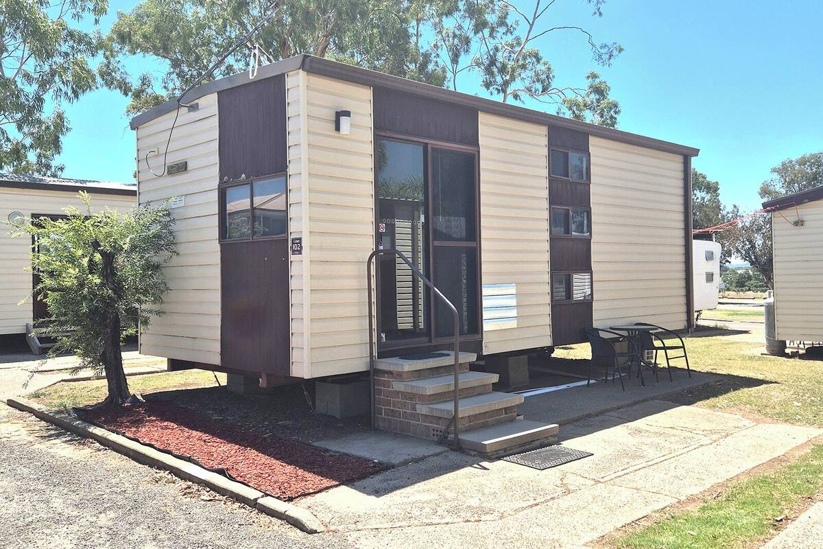 A small, single-story mobile home with a front door, a small porch, and a window.