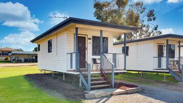 A single-story mobile home with a covered porch, a staircase, and a small front yard.