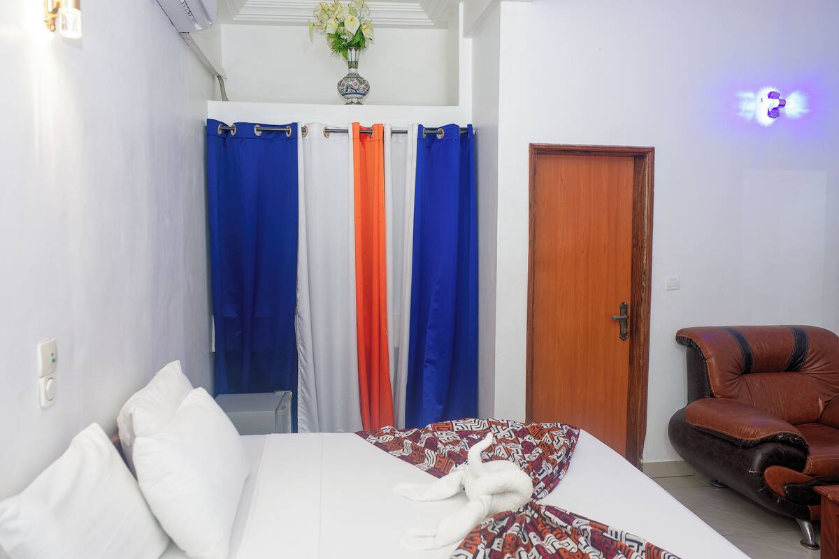 A bedroom with a bed, a wooden door, and a leather chair.