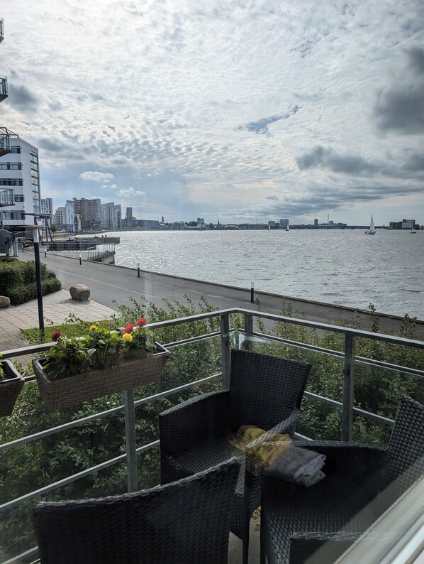 A balcony with wicker furniture overlooking a waterfront with sailboats. - Apartment with stunning views of the Limfjord (Aalborg)