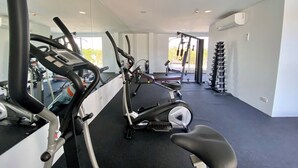 Un gimnasio con máquinas de cardio, equipo de levantamiento de pesas y una cinta de correr.