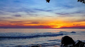 Una puesta de sol sobre el océano, con olas y rocas al frente.