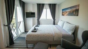 Un dormitorio con una cama, un televisor y un cuadro en la pared.