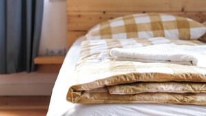Cama bem arrumada com travesseiro xadrez e toalha branca dobrada.