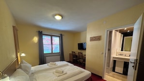 A hotel room with a bed, a desk, a television, and a bathroom.