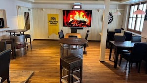 A restaurant with a large TV screen displaying a fire, wooden floors, and a yellow banner.