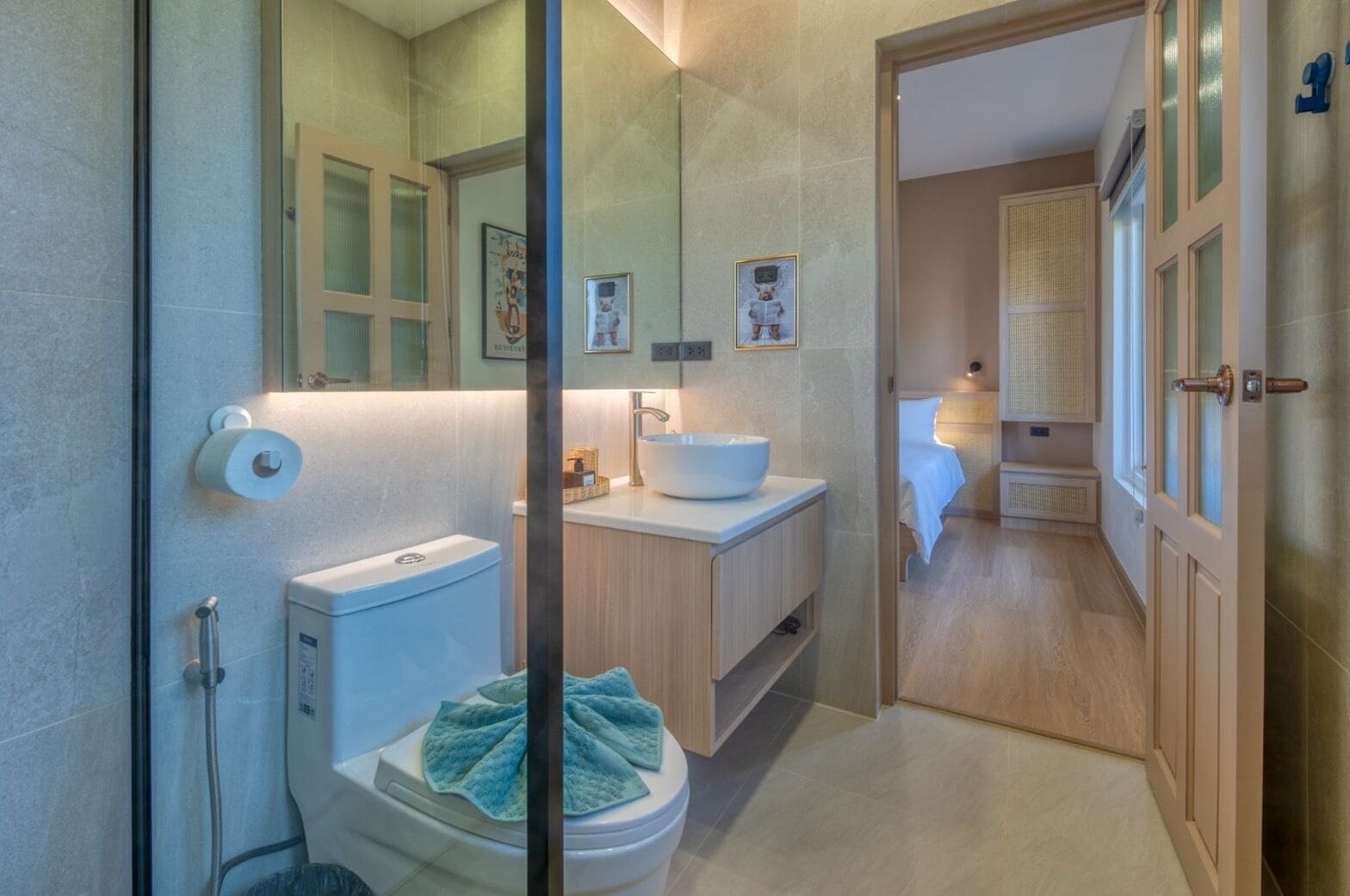 Un baño moderno con inodoro, lavamanos y ducha. Hay una toalla sobre el asiento del inodoro y un espejo sobre el lavamanos.
