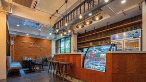 Interior moderno de una cafetería con pared de ladrillo, mostrador de madera y zona de estar.