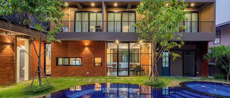 Un edificio moderno con piscina, puertas de vidrio y fachada de ladrillo.
