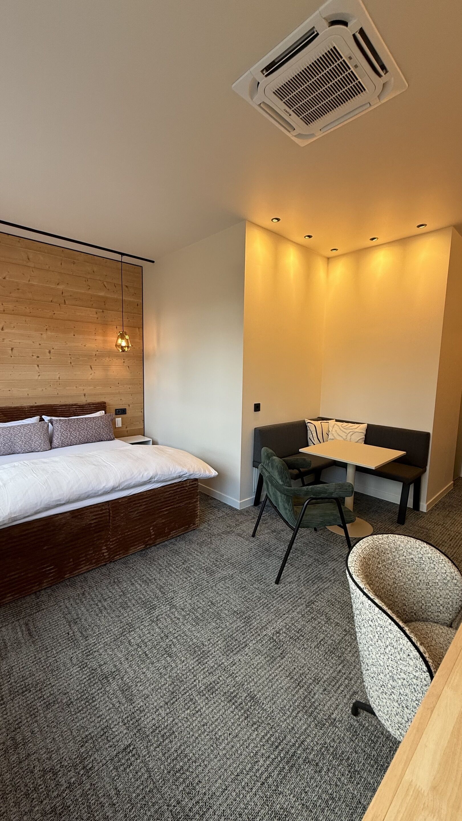 Una habitación de hotel moderna con una cama, una pequeña mesa, un sofá y una silla.
