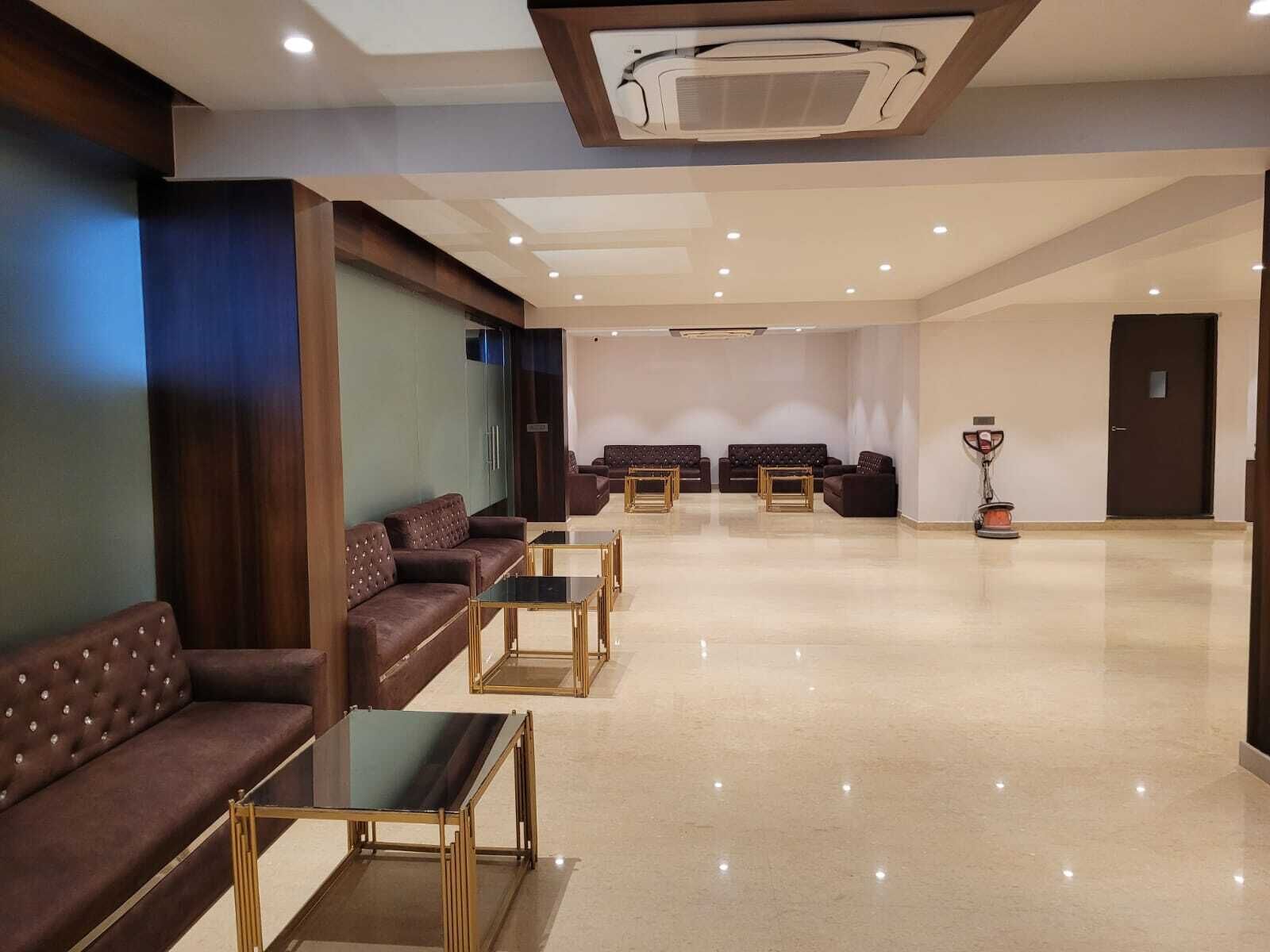 A spacious lobby with leather sofas, glass-top tables, and a large air conditioning unit on the ceiling.
