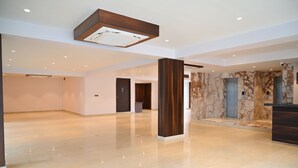 Eine geräumige, moderne Lobby mit poliertem Boden, einer Holzsäule, Marmorwänden und einer Decke mit Einbaustrahlern.