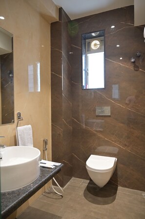 A modern bathroom with a marble wall, a sink, and a toilet. - Kitty House (Kolkata)