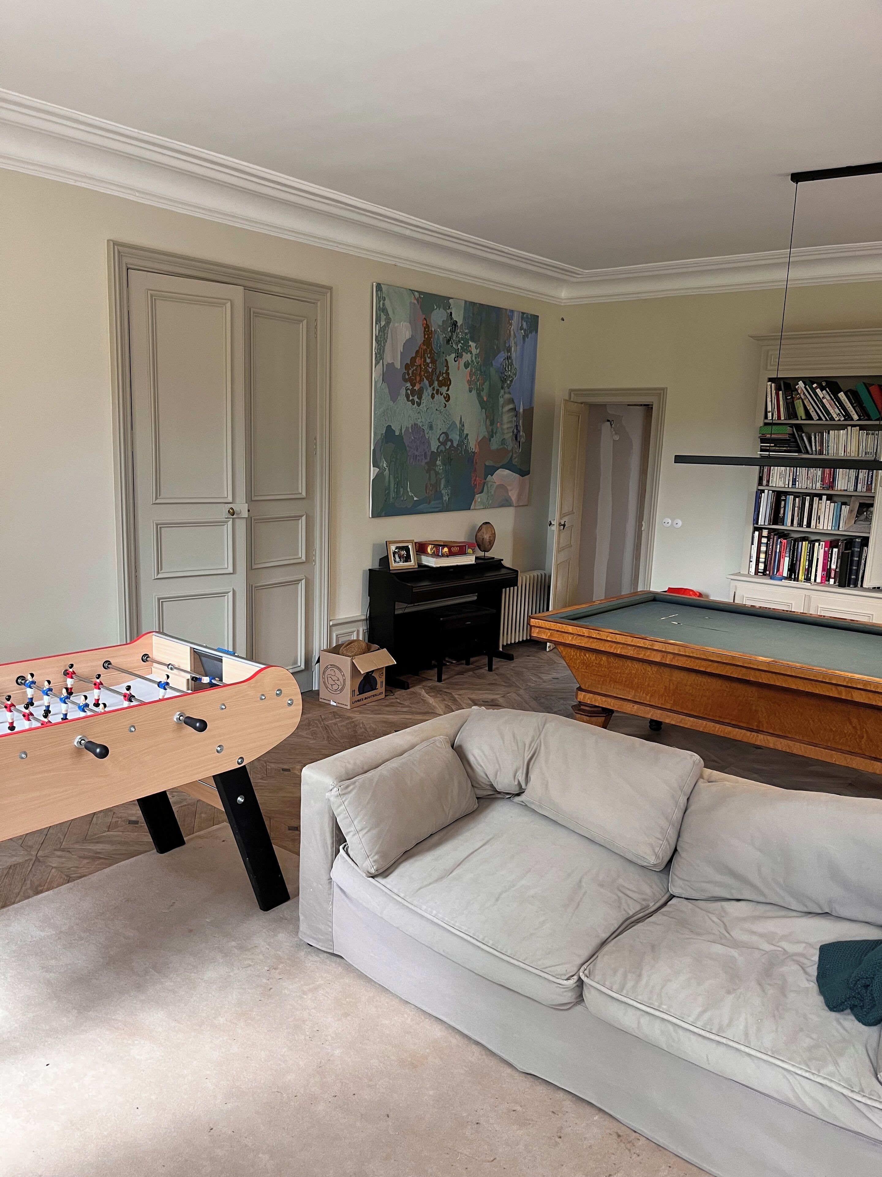 Una sala de estar con mesa de fútbol de mesa, mesa de billar, sofá y estantería.