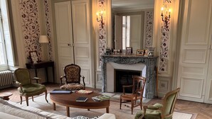 Een klassieke woonkamer met een open haard, behang met patroon en tijdloze meubels.