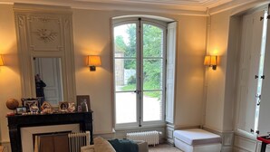 Een woonkamer met een bank, een salontafel, een open haard en een groot raam.