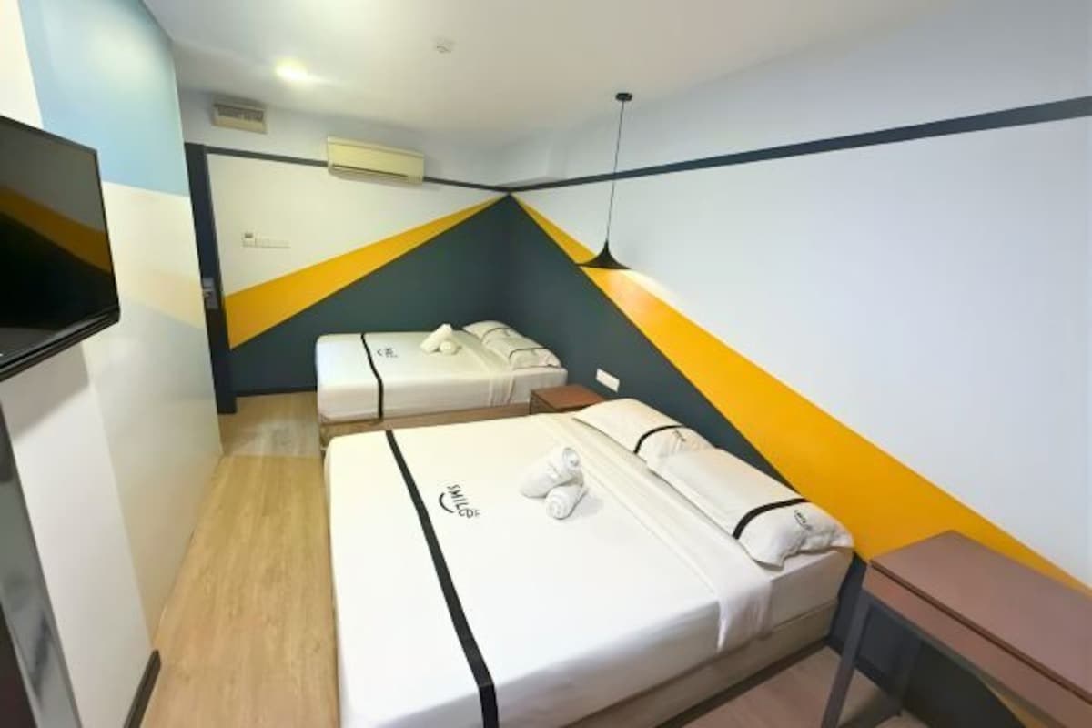 A hotel room with two beds, a TV, and a desk.