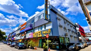 Un hotel con un llamativo letrero que dice 'HOTEL SMILE', varios pisos y un cielo despejado.
