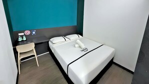 A small hotel room with a bed, a desk, a chair, and a teal accent wall. - Smile Hotel SS2 Petaling Jaya (Petaling Jaya)