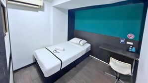 A single bed with a white mattress and black trim, a small desk with a chair, a teal-colored wall, and a window. - Smile Hotel SS2 Petaling Jaya (Petaling Jaya)