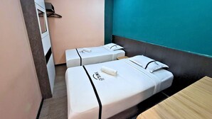Habitación de hotel con dos camas, una mesa de madera y una pared de acento color verde azulado.