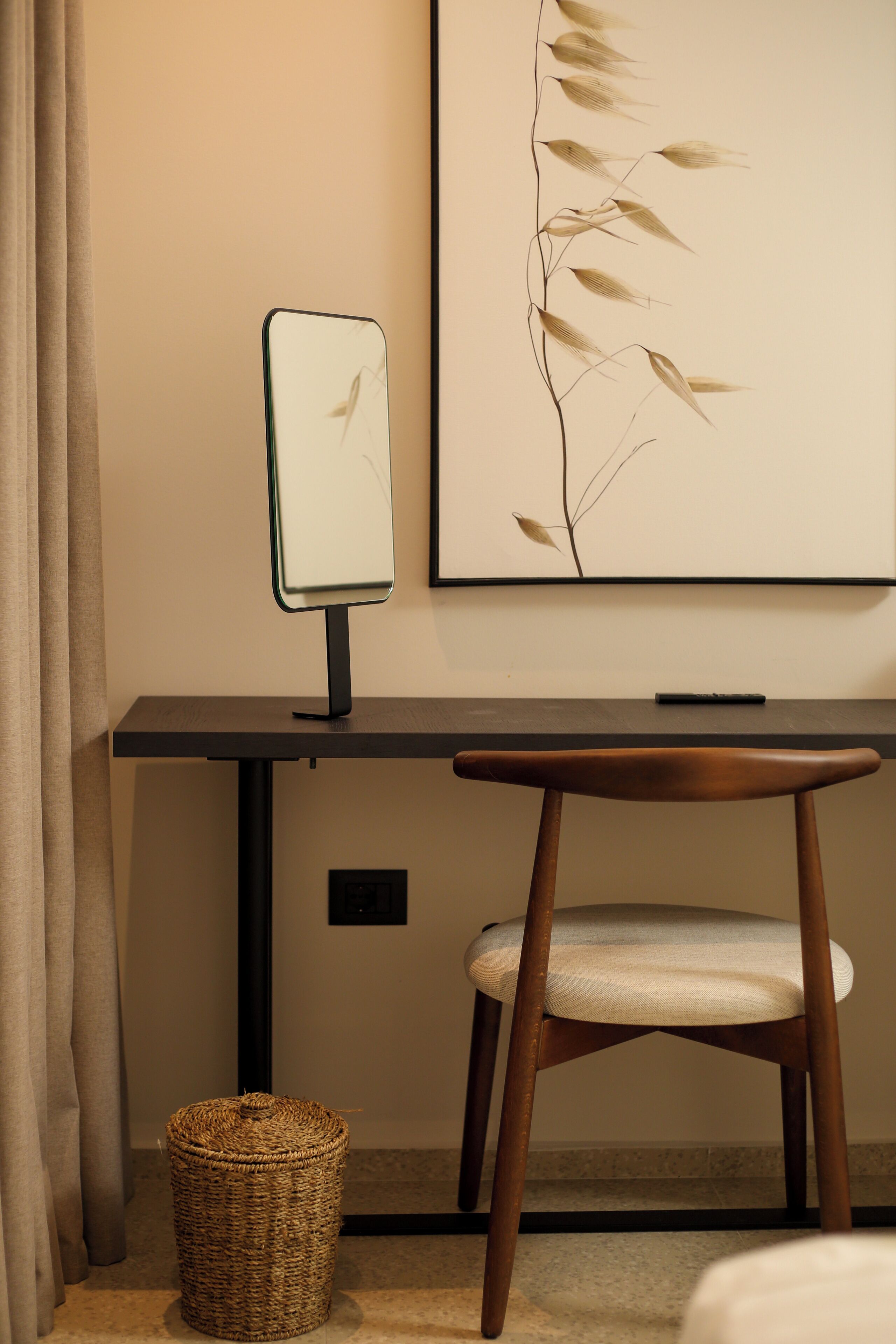 A room with a desk, chair, and a wall-mounted mirror.
