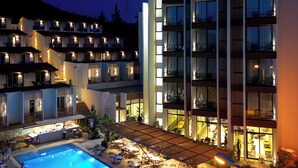 Een hotel met een zwembad, terras en meerdere balkons.