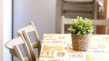 A dining table with a woven plant holder and a tablecloth with various logos.