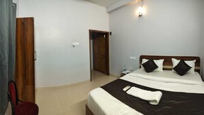 Ein Schlafzimmer mit einem Bett, einer Holztür, einem roten Stuhl und einem durch eine geöffnete Tür einsehbaren Badezimmer.
