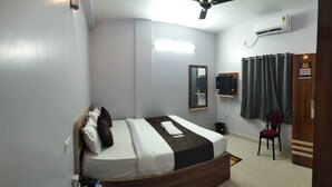 Ein Hotelzimmer mit einem Bett, einem Deckenventilator, einem Spiegel, einem Fernseher und einem Kleiderschrank.