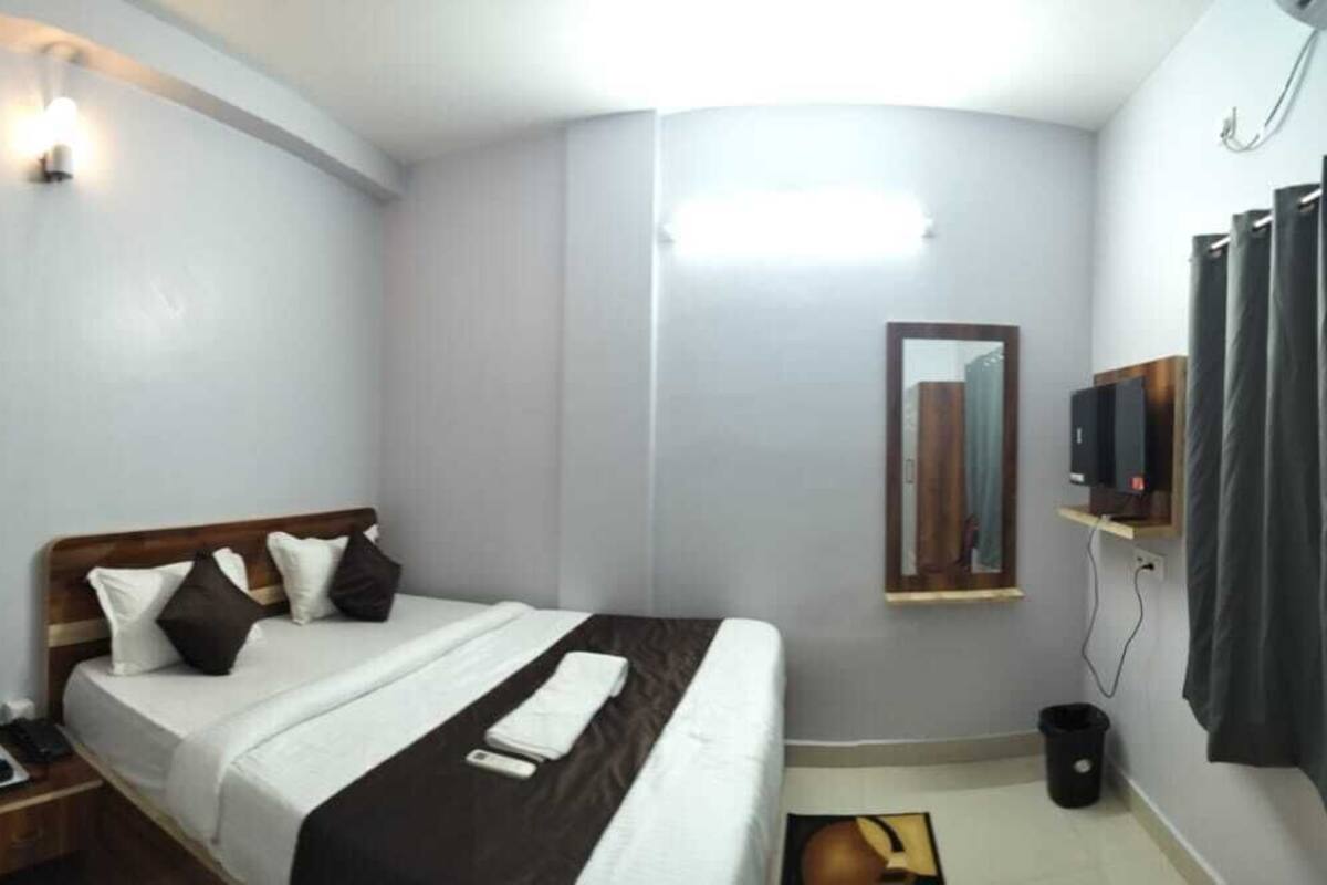 A hotel room with a bed, bedside table, lamp, and a mirror.