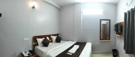 A hotel room with a bed, bedside table, lamp, and a mirror.