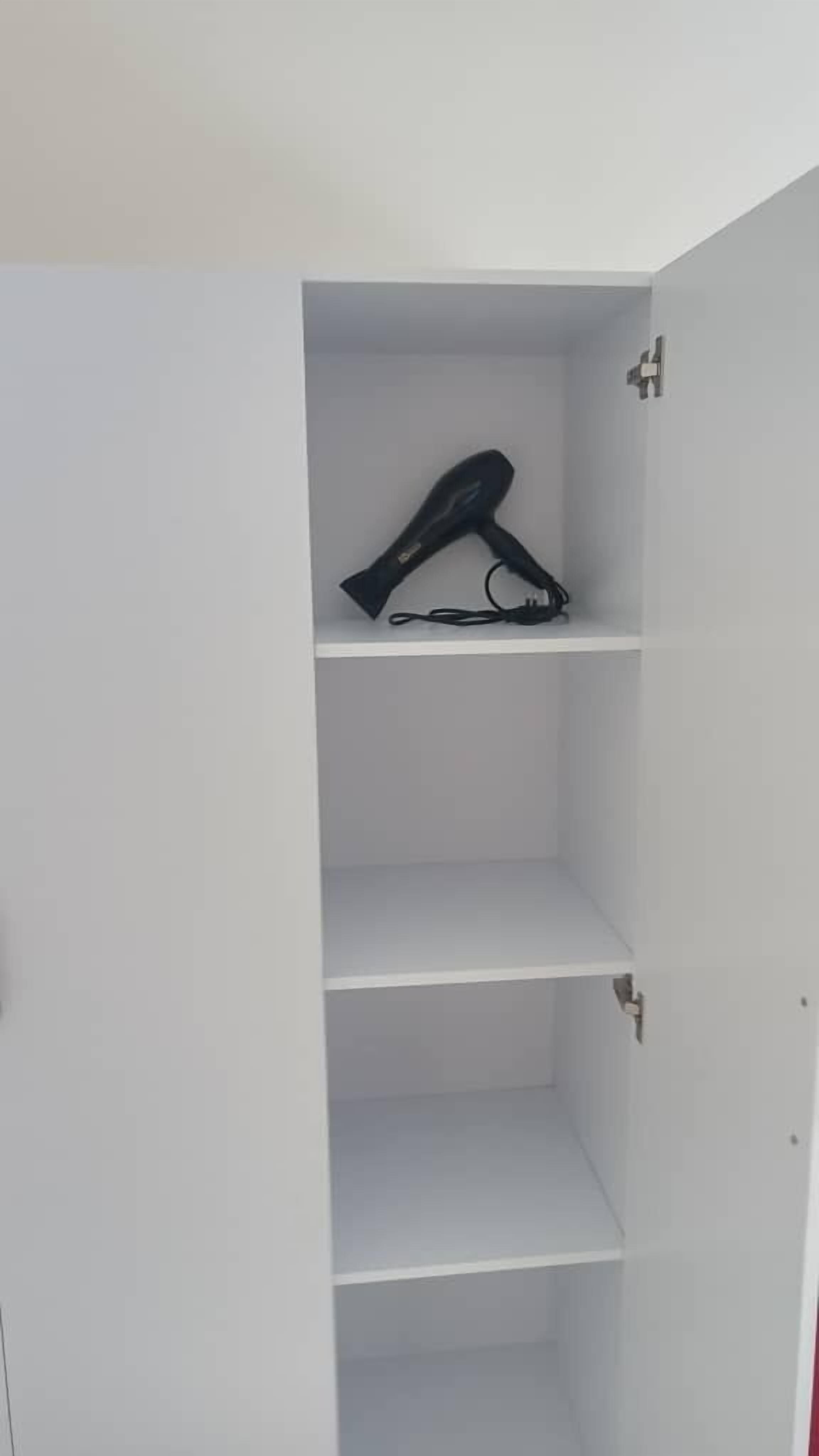 A white wardrobe with three shelves and a hanging space.