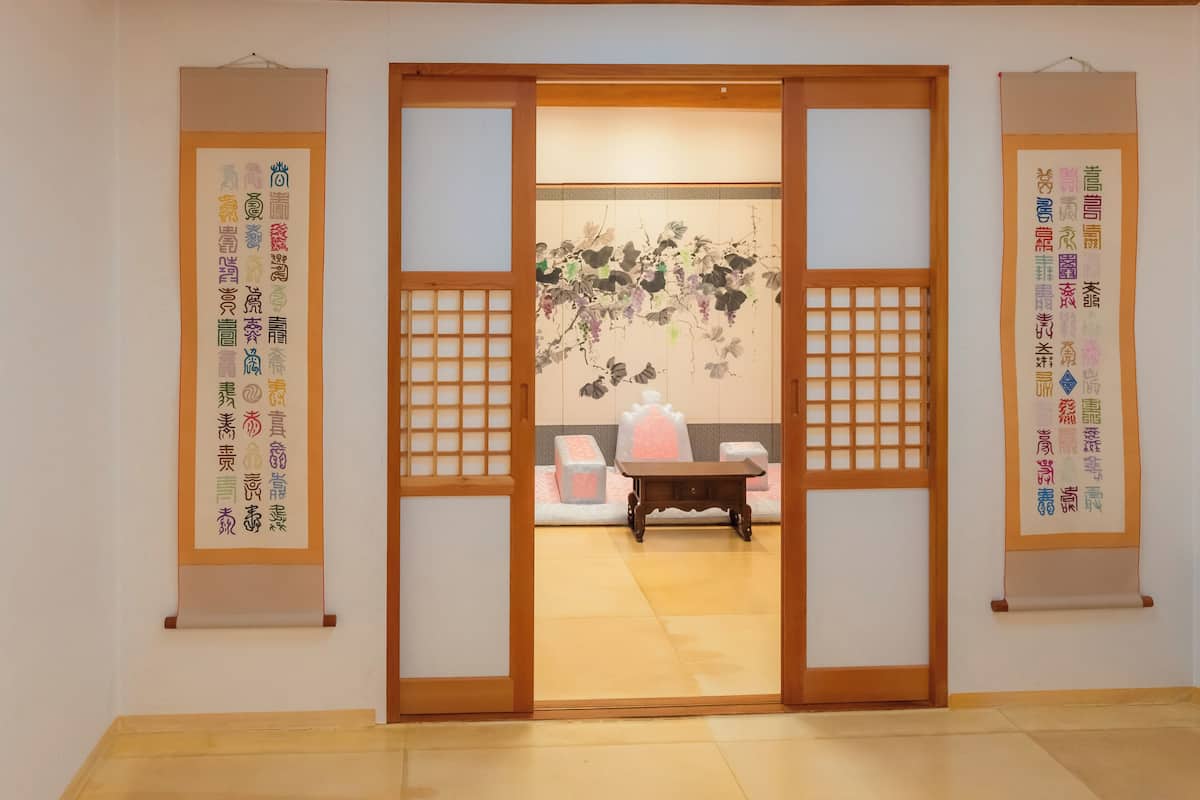 Una habitación japonesa tradicional con puertas correderas, suelo de esteras de tatami y rollos de caligrafía en las paredes.