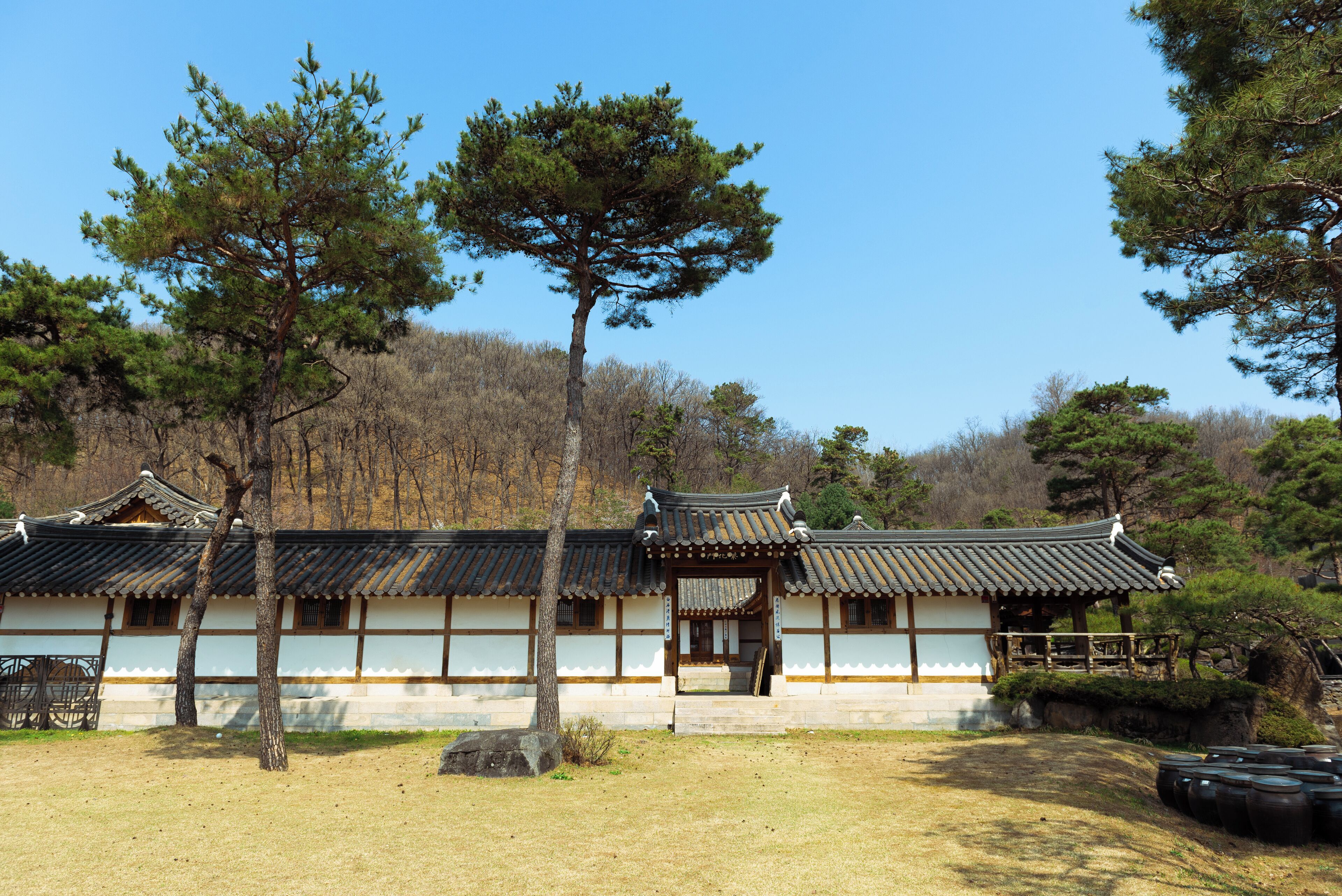 A traditional Korean building with a tiled roof, wooden beams, and a stone base.