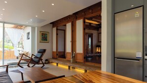 Una cucina moderna con frigorifero in acciaio inossidabile, pavimento in legno e un angolo relax con tavolo e sedie di legno.